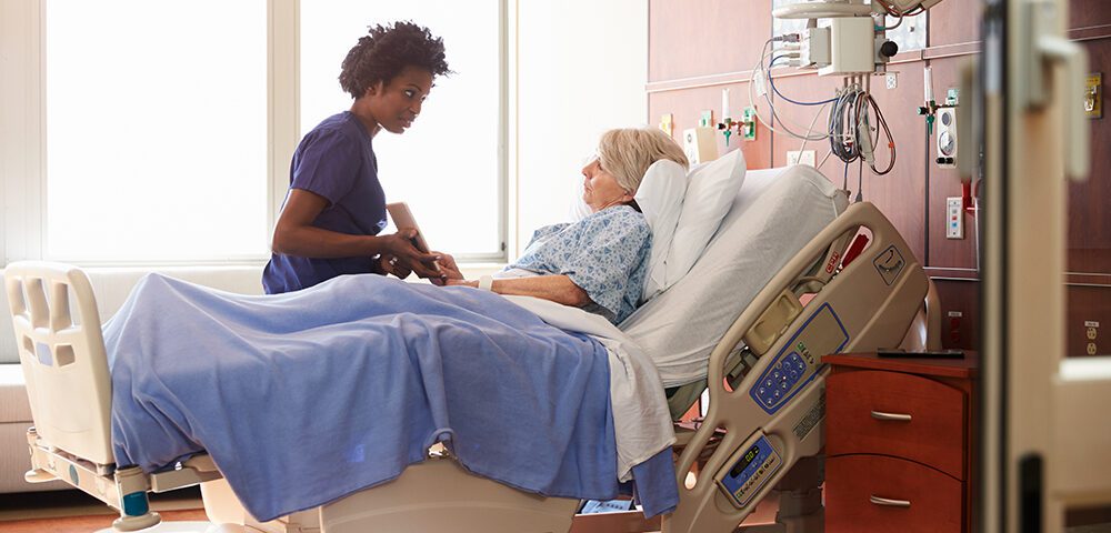 Nurse talking to elderly lady patient in bed